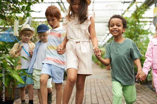 happy multi-ethnic group of children have fun, walk in garden or greenhouse, get to know the world around them, the greenhouse is a great place for an excursion