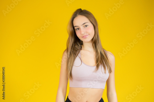 Close up image of attractive fit young woman over yellow background. © Danko