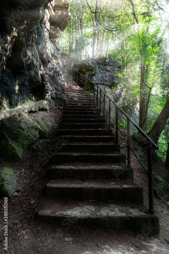 The afternoon sun shines brightly on a stairway on the side of a cliff in a forest, leading to the top of the Elora Gorge in Ontario. © John