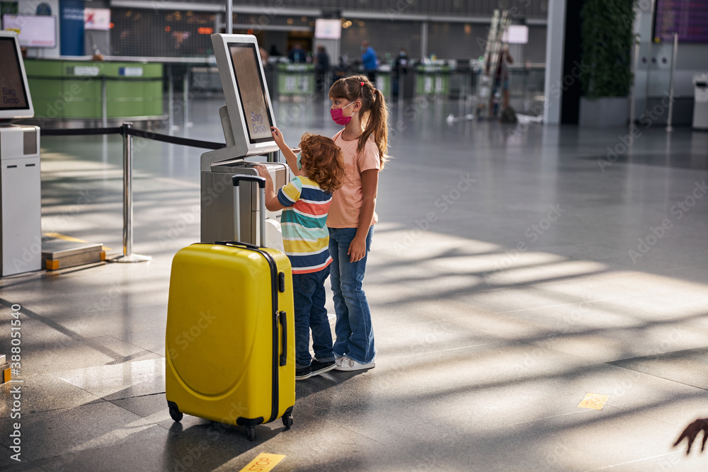 Siblings are using self-service baggage drop machine Siblings are using self-service baggage drop machine