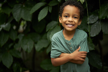 portrait of adorable black child boy near plants, african kid boy look at camera and smile, in the forest