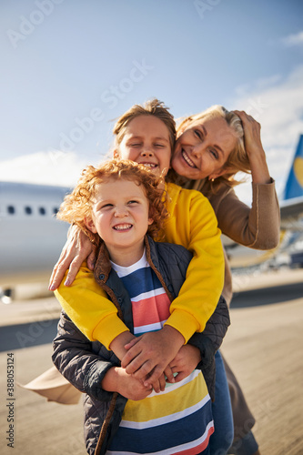 Smiling siblings with their mother close to an aircraft