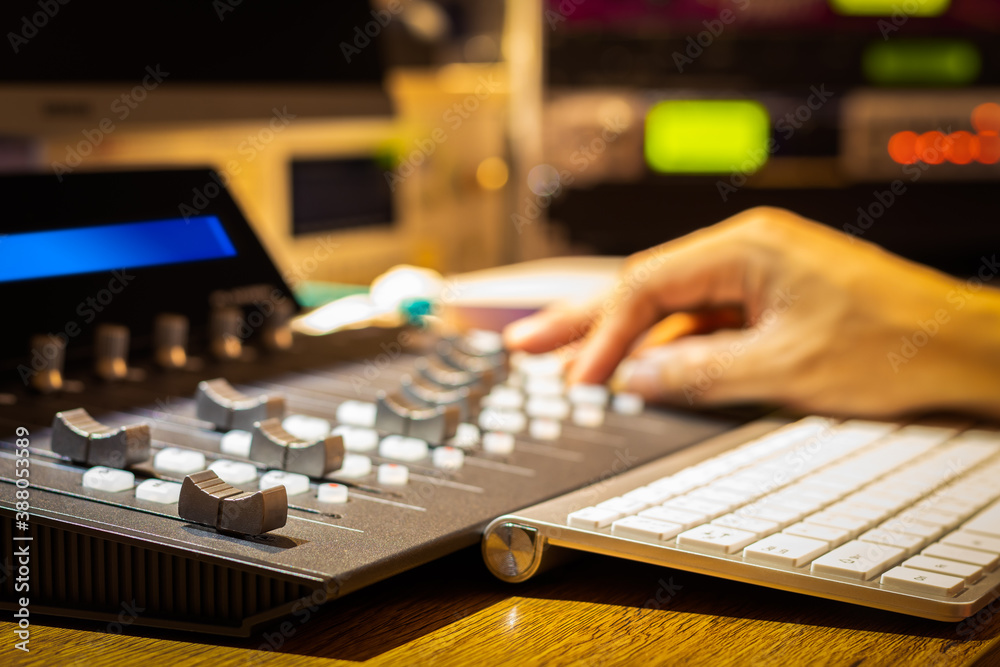 male sound engineer hand adjusting fader on digital control surface for mixing audio track on computer in sound studio or broadcasting studio. focus on first fader male sound engineer hand adjusting fader on digital control surface for mixing audio track on computer in sound studio or broadcasting studio. focus on first fader