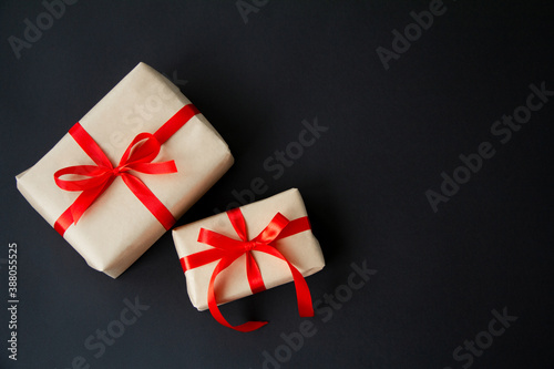Gift boxes tied with red ribbons on a black background, Christmas decoration, gift wrapping. Top view with copy space