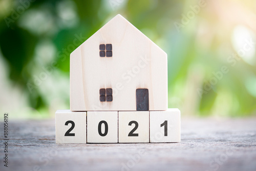 House model standing on wood block number 2021 concept for new house, new year property, property concept isolated on sunlight bokeh background.
