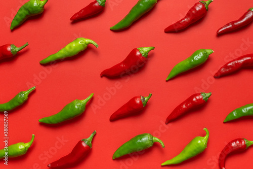 Hot red and green fresh chili peppers on red background flat lay top view. Seasoning for dish, spicy spices for cooking, cayenne pepper, food. Creative layout, chili pattern