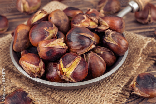 Chestnuts in a pan on a wooden background. Rustic style