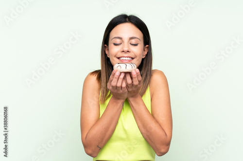 Woman over isolated green background holding a donut