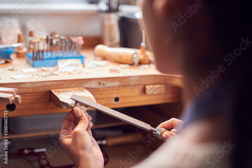 Close Up Of Female Jeweller Working On Ring With File In Studio