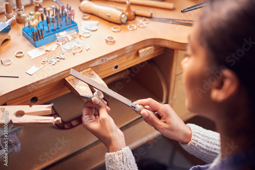 Close Up Of Female Jeweller Working On Ring With File In Studio