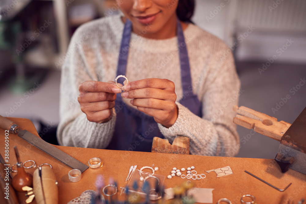 Close Up Of Female Jeweller At Bench Checking Ring She Is Working On In Studio - obrazy, fototapety, plakaty 