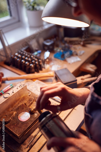 Fototapeta Naklejka Na Ścianę i Meble -  Close Up Of Male Jeweller Working On Brooch With Blowtorch In Studio