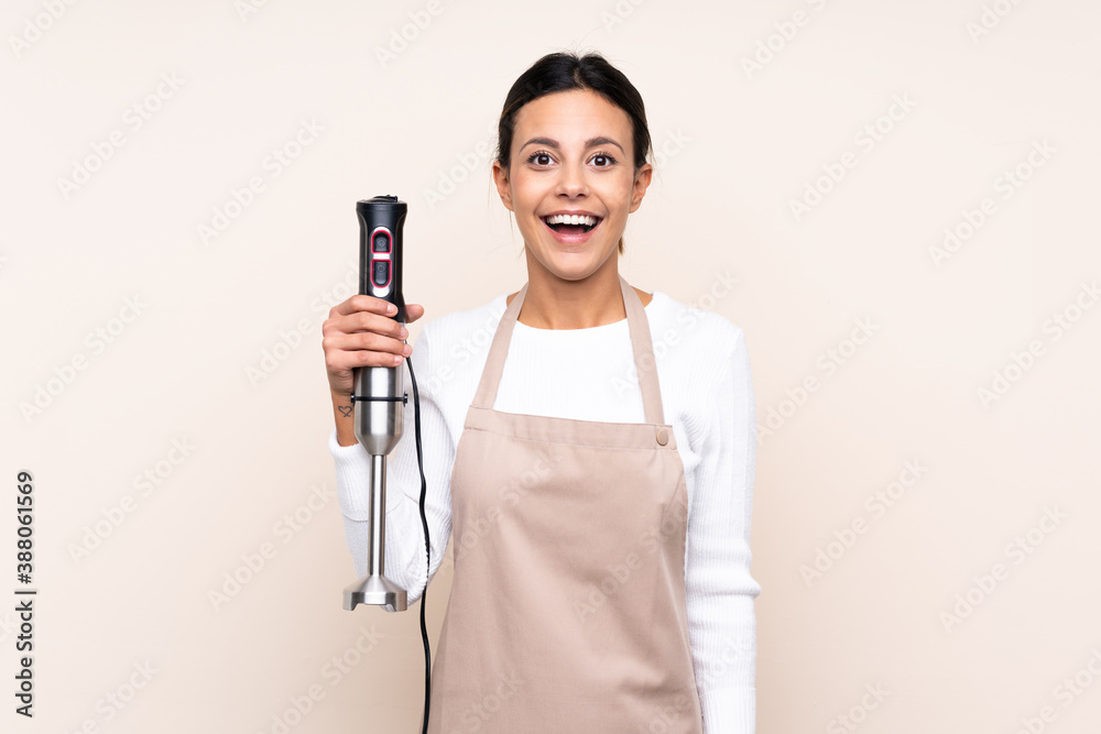 Woman using hand blender over isolated background with surprise and shocked facial expression Woman using hand blender over isolated background with surprise and shocked facial expression