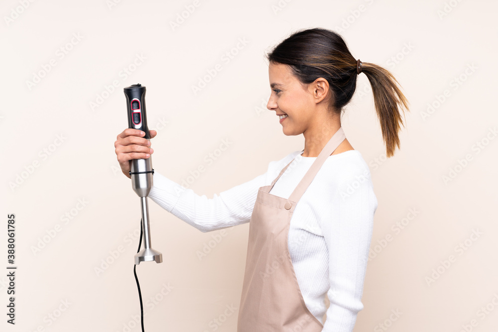 Woman using hand blender over isolated background with happy expression Woman using hand blender over isolated background with happy expression
