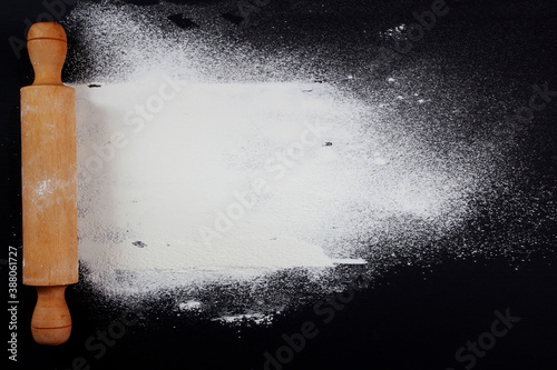 cake roller and flour on black table background