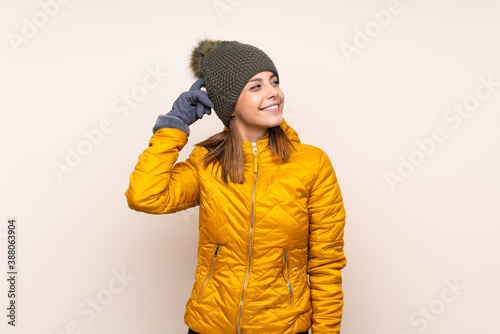 Woman with winter hat over isolated background having doubts and with confuse face expression