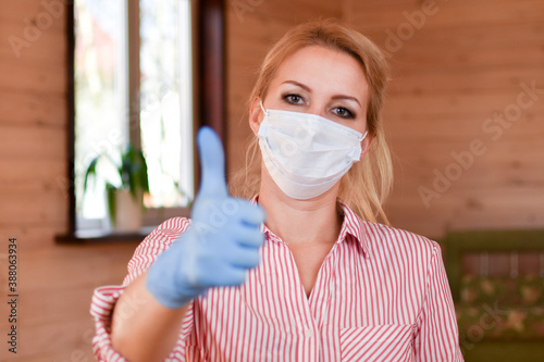 Woman in medical mask and gloves shows thumbs up. medical person shows like.