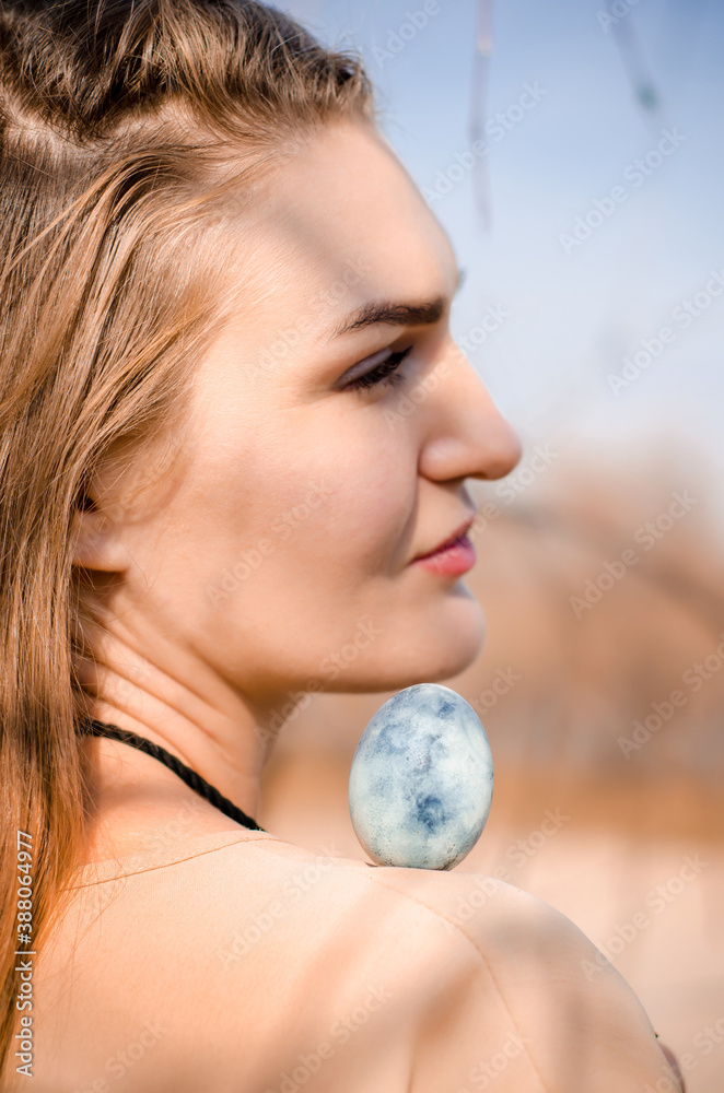 Young blonde girl in boho style, with blue egg on her shoulder like dragon egg, photo for cover of book, movie or album Young blonde girl in boho style, with blue egg on her shoulder like dragon egg, photo for cover of book, movie or album