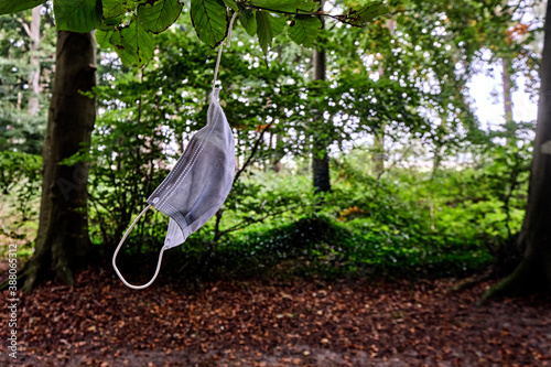 Eine benutzte Gesichtsmaske hängt an einem Baum. photo