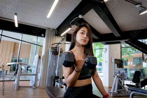 Young slim woman doing exercises with dumbbell in gym