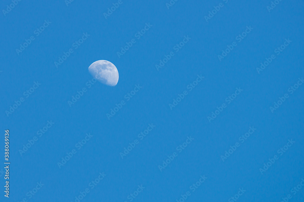 Half-circle of the moon in the blue daytime sky. Half-circle of the moon in the blue daytime sky.