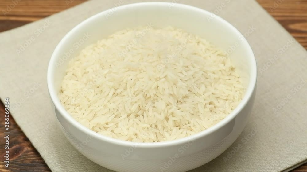 White rice raw grains falling into a white bowl, slow motion, close up White rice raw grains falling into a white bowl, slow motion, close up