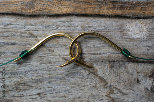 Two fishing hooks tied with fishing line on a wooden background.
