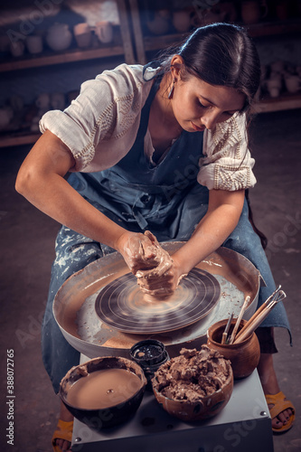 Charming potter master woman works with clay on a potter's wheel. Hand work. photo