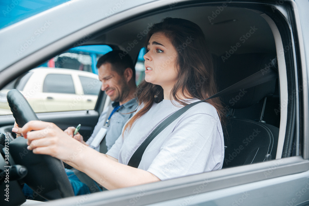 Nervous upset woman can't take driving exam. Car accident during driving lesson concept. Usatisfied male instructor notices something bad in his paper. Failed driving license exam concept.