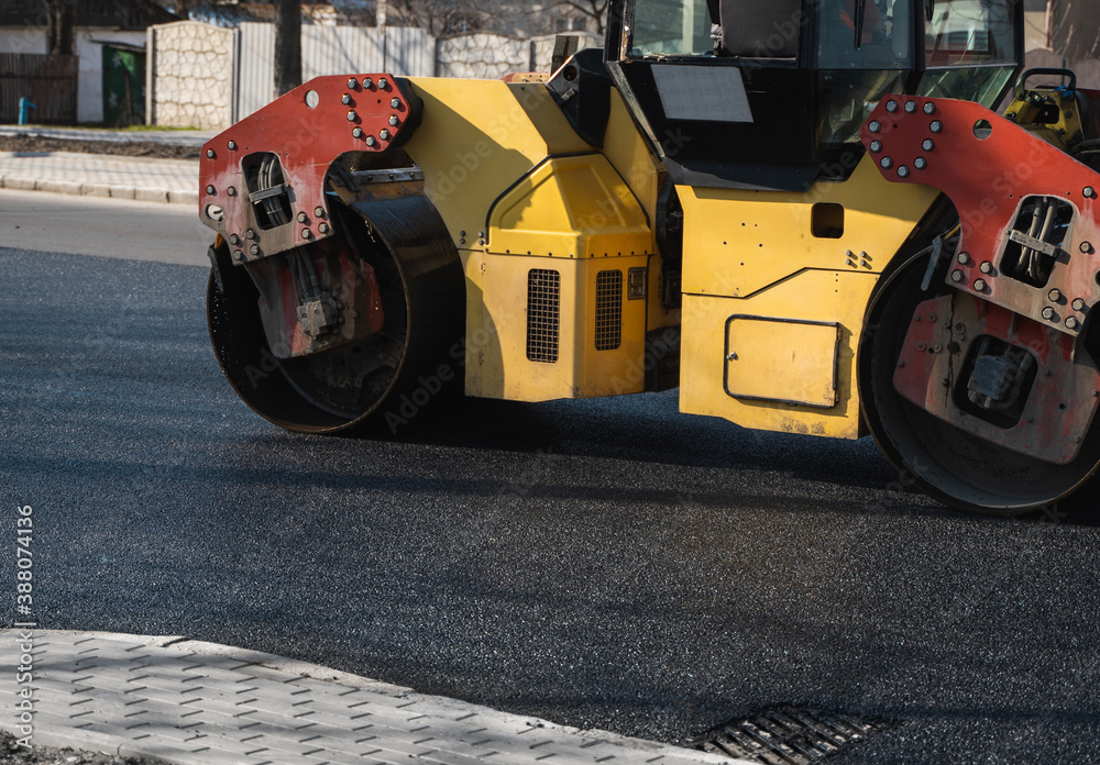 Asphalt road roller with heavy vibration roller compactor press new hot asphalt on the roadway on a road construction site. Heavy Vibration roller at asphalt pavement working. Repairing.