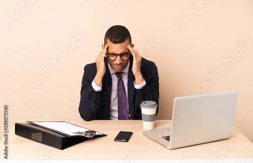 Young business man in his office with a laptop and other documents with headache