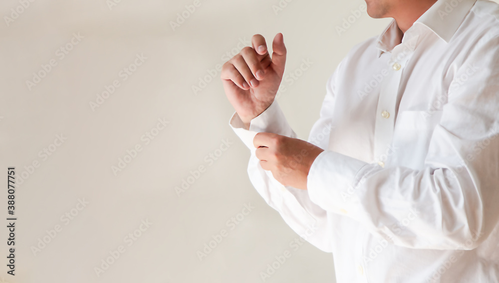 a man puts on a clean, elegant white shirt, buttons up his sleeves.