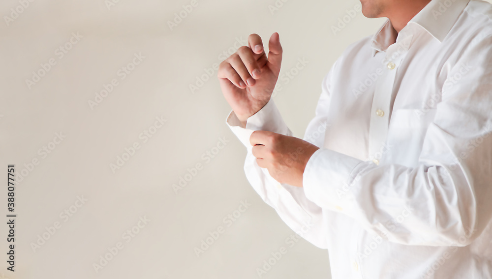 Fototapeta premium a man puts on a clean, elegant white shirt, buttons up his sleeves.