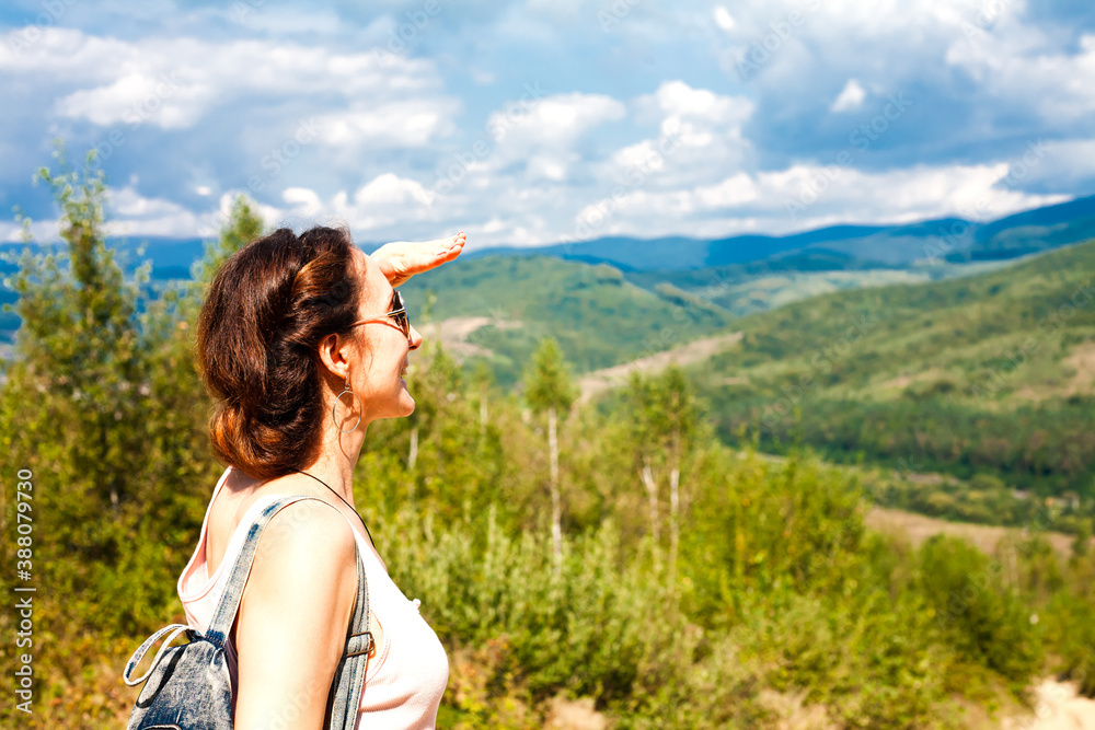 Happy young woman looking on beautiful mountain landscape. Vacation in the mountains. Concept of hiking. Copy space.