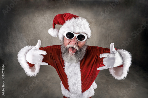 Rock and roll santa with tongue sticking out wearing sunglasses and hands in rock gesture