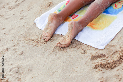 Child laying on a towel at the beach with sandy toes and feet photo