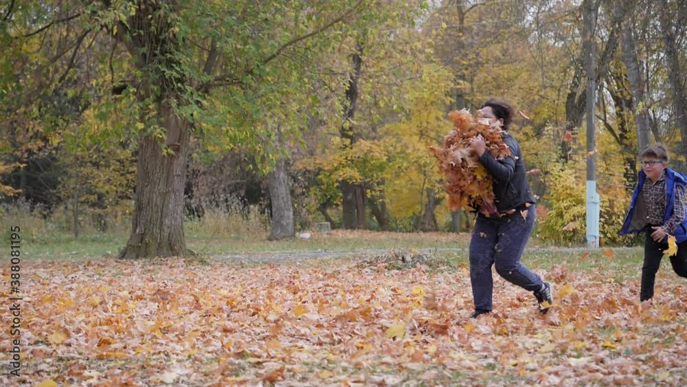 Outdoor games. Autumn landscape. Autumn. Children play with fallen leaves of trees. Boy runs through a cloud of floating autumn yellow leaves. Outdoor games. Autumn landscape. Autumn. Children play with fallen leaves of trees. Boy runs through a cloud of floating autumn yellow leaves.