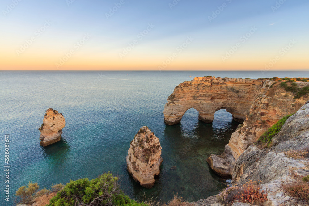 Algarve in Portugal and its amazing beaches, is a summer holiday destination for many tourists in Europe. Landscape with cliffs on the coast at colorful sunset. Pure nature, blue sea, sand.