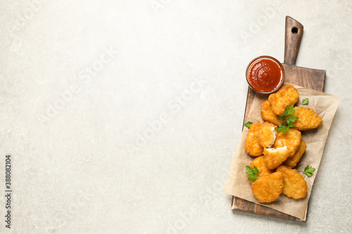 Tasty fried chicken nuggets on light grey table, top view. Space for text photo