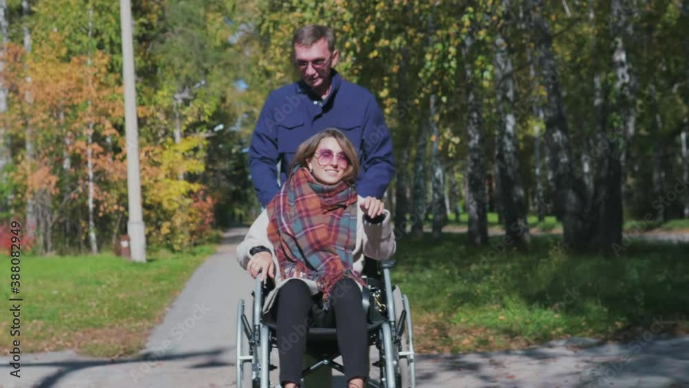 Man walking with woman on wheelchair Man walking with woman on wheelchair