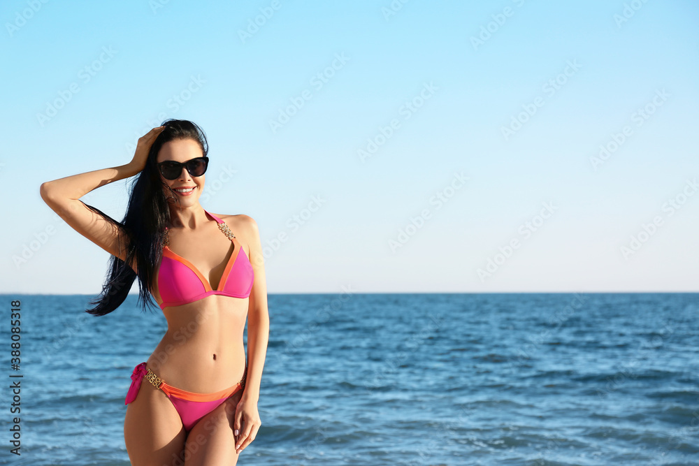 Beautiful young woman in pink stylish bikini on beach. Space for text