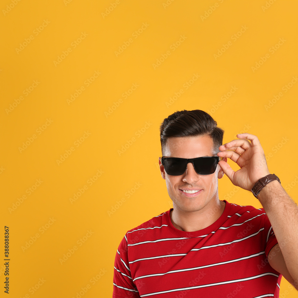 Handsome man wearing sunglasses on yellow background. Space for text Handsome man wearing sunglasses on yellow background. Space for text
