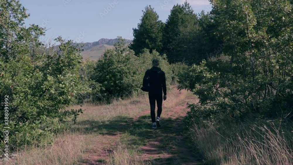 Man walking through a forest path. Person going on a hike through the woods. Man walking through a forest path. Person going on a hike through the woods.