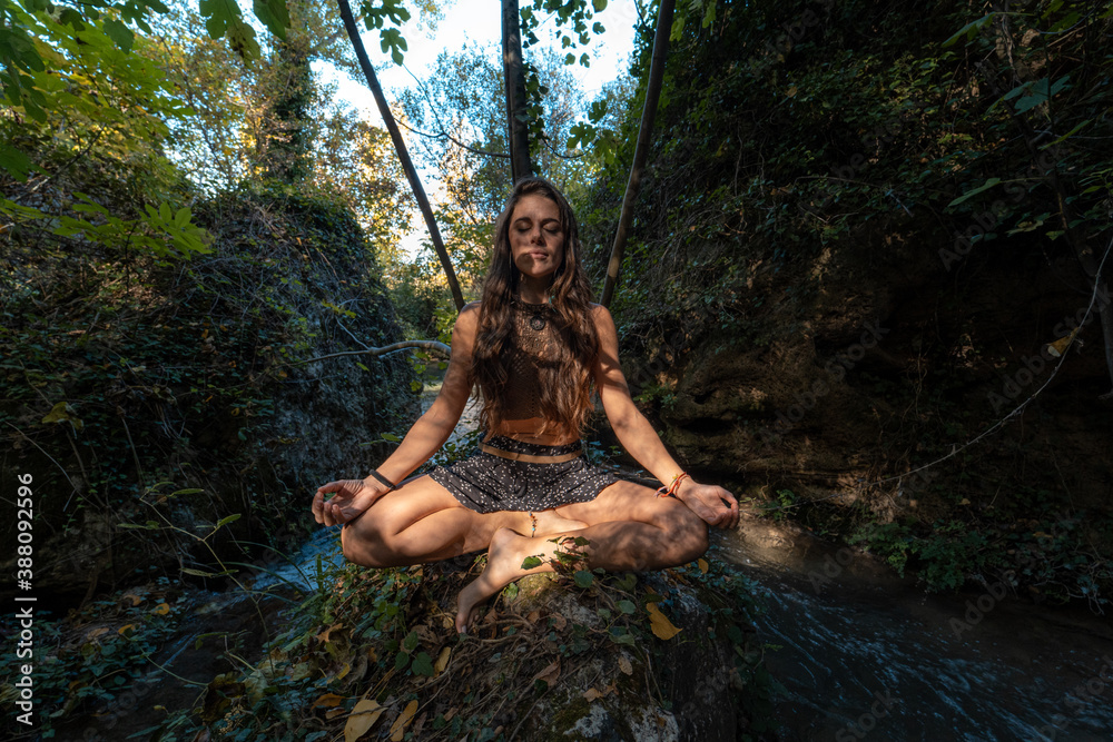 Fototapeta premium Strong woman practicing yoga in nature with a beautiful sunset.
