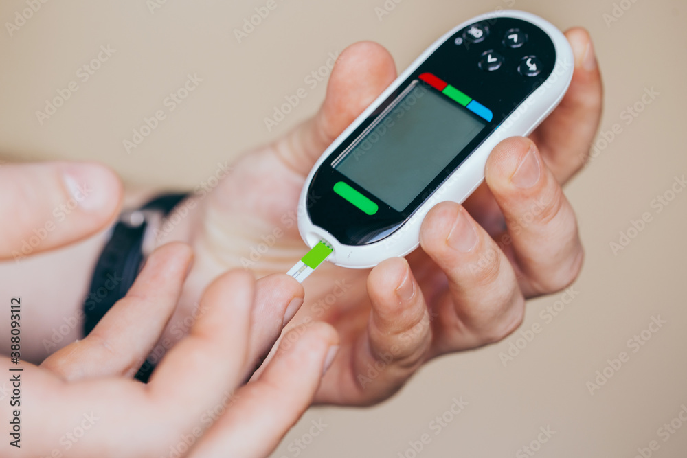 Fototapeta premium diabetes, healthcare - close up of a man with a glucometer and a test strip checking blood sugar at home