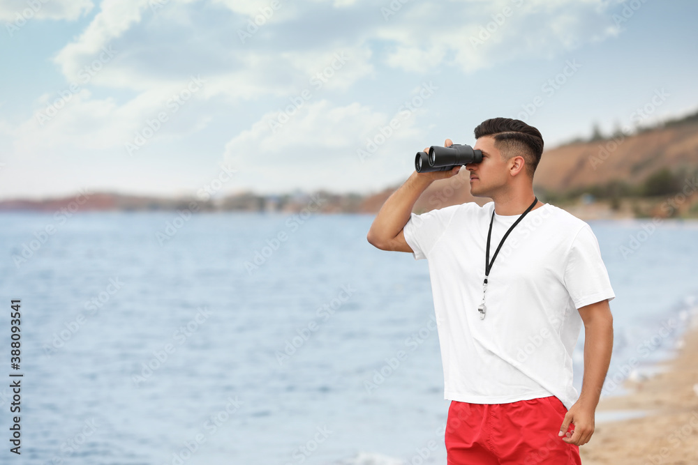 Obraz premium Handsome male lifeguard with binocular near sea