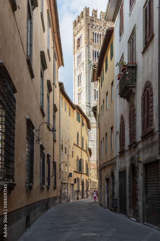 Street in Lucca, a city in Tuscany in Italy, on the background the bell tower of the Basilica of San Frediano.