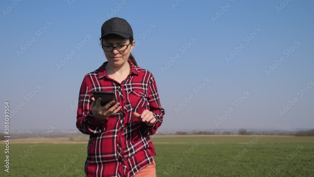 girl farmer red neck with a digital tablet walking on land for sowing on a green field. eco farming agriculture lifestyle concept. woman worker studies winter green wheat crops works in field girl farmer red neck with a digital tablet walking on land for sowing on a green field. eco farming agriculture lifestyle concept. woman worker studies winter green wheat crops works in field