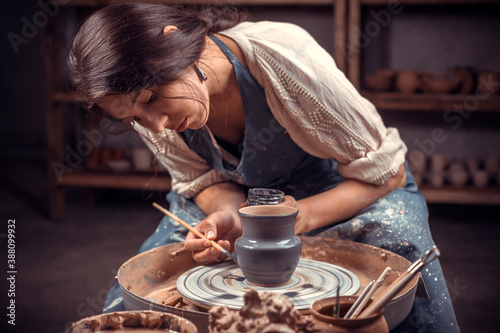 Charming female master working with pottery at the ceramic workshop. Handwork.