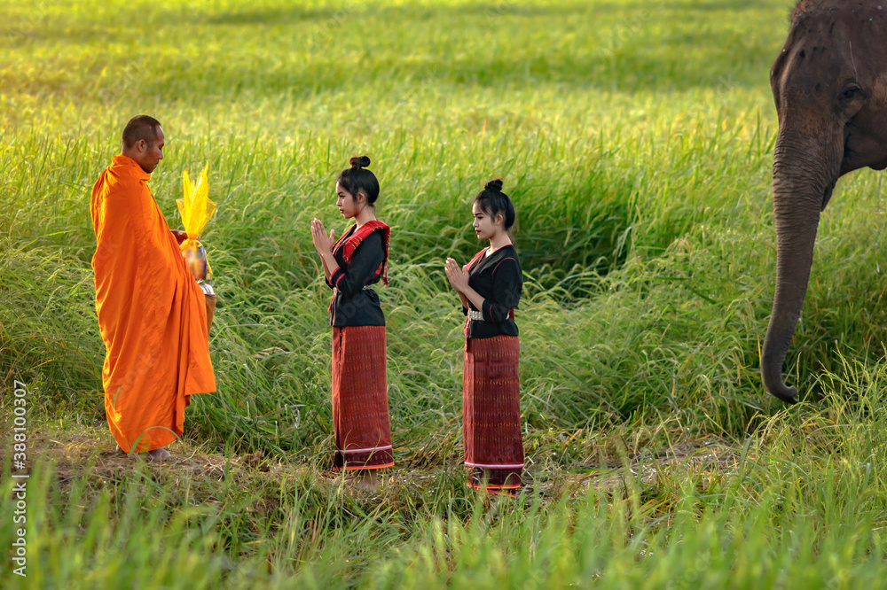 Φωτογραφία Thai twin girls In traditional Thai dress Is making merit to the monks accompany